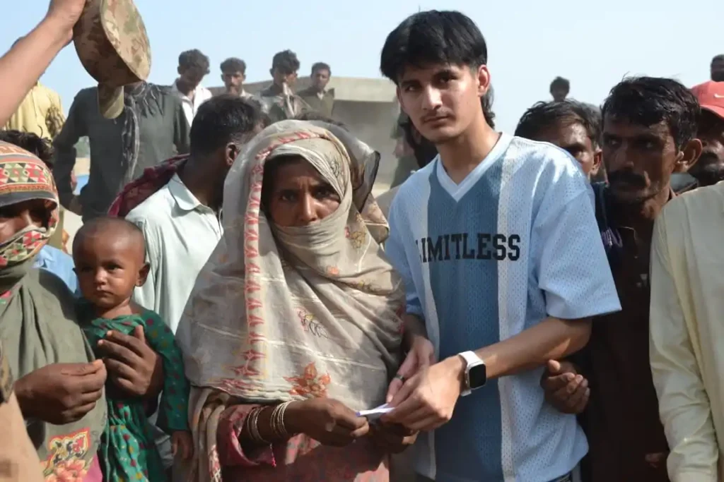 A volunteer offers relief goods to a woman impacted by Muzaffargarh floods.